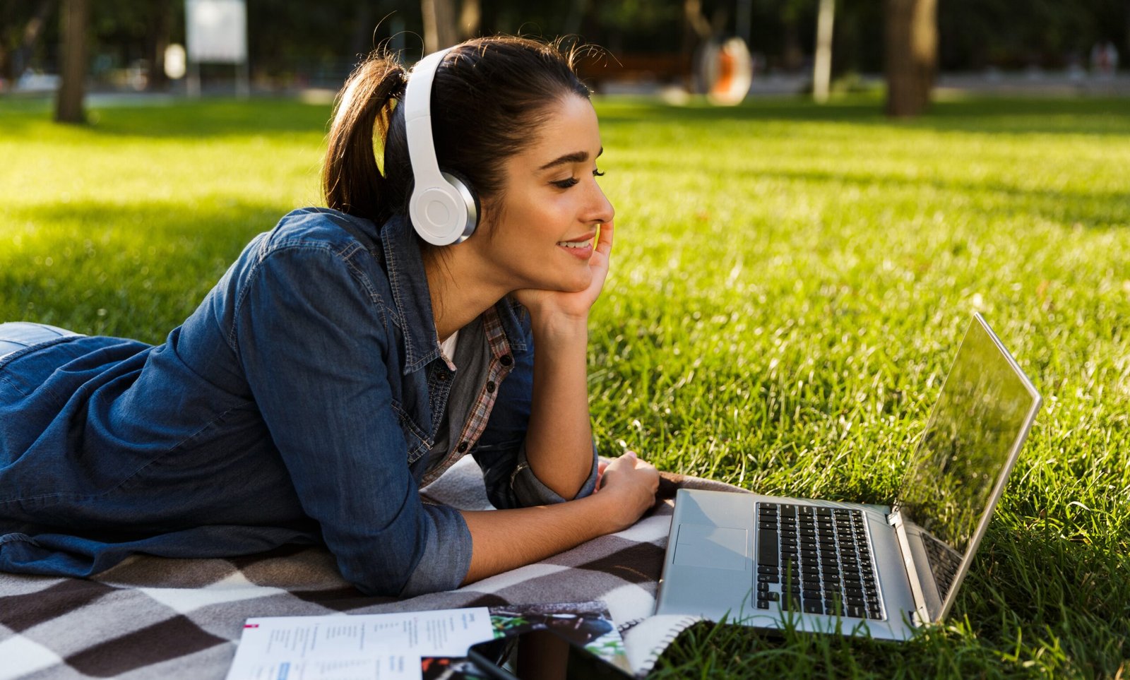 Beautiful young woman student in the park using laptop computer.